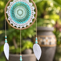 Turquoise dream catcher hanging in a garden with flower pots in the background – spiritual décor from CardsAmoreStore.
